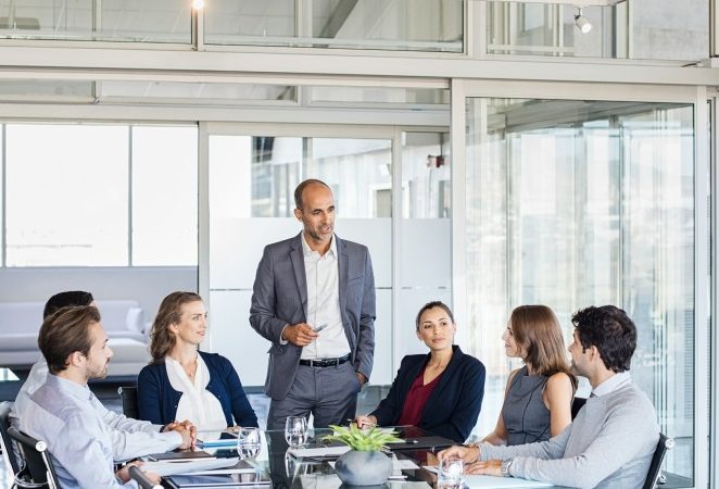 Human resource manager training people about company and future prospects. Group of businesspeople sitting in meeting room and listening to the speaker. Leader man training his work group in a conference room.